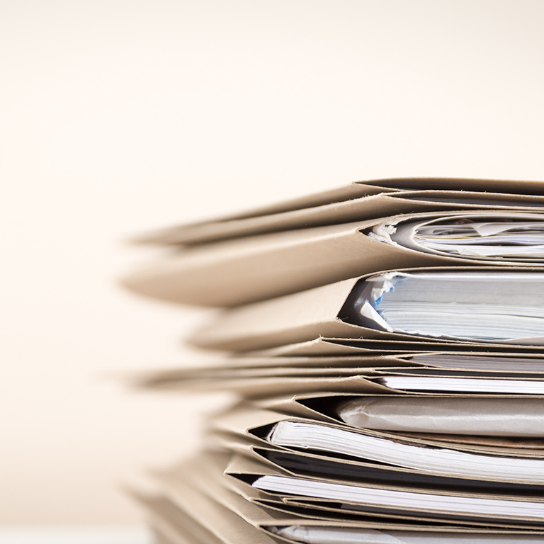 Closeup of stack of document folders on a desk waiting to be completed
